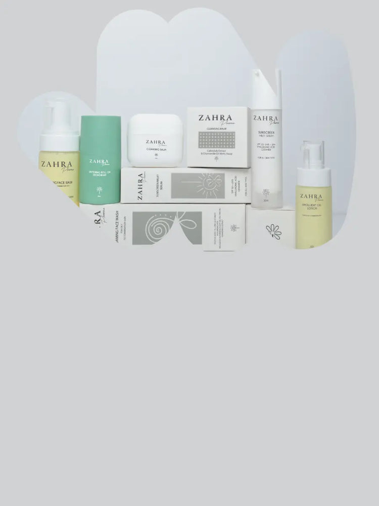 A collection of Zahra skincare products and their packaging boxes arranged on a light gray background with soft white abstract shapes behind them. The products include bottles, jars, and boxes in white, pale yellow, mint green, and gray.